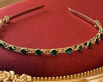 Bandeau diadème doré avec cristaux verts.