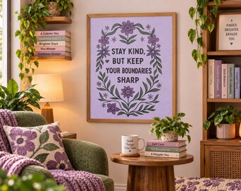 May include: A rectangular wall art print in a light wooden frame featuring a lavender background with a dark green floral wreath and the text "STAY KIND, BUT KEEP YOUR BOUNDARIES SHARP" in black capital letters, centered on a wall.