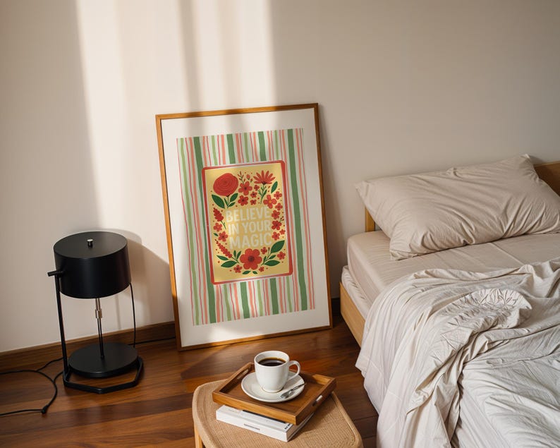 May include: A framed rectangular wall art print featuring a yellow center panel with red and orange flowers, green leaves, and the text BELIEVE IN YOUR MAGIC, surrounded by a background of vertical green, pink, and white stripes in a wooden frame.