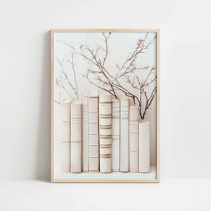 May include: A framed print of a white background with a row of white books and a delicate floral design in shades of brown and white.