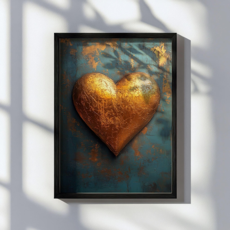 May include: A framed artwork featuring a textured, golden heart against a teal and gold background. The heart has a metallic appearance, and the frame is black. The artwork is displayed on a white wall, with shadows from a window.