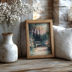 May include: A wooden picture frame with a vintage print of a garden scene. The print features a bench under a trellis with pink flowers and a cascading purple flower. The frame is sitting on a wooden surface.