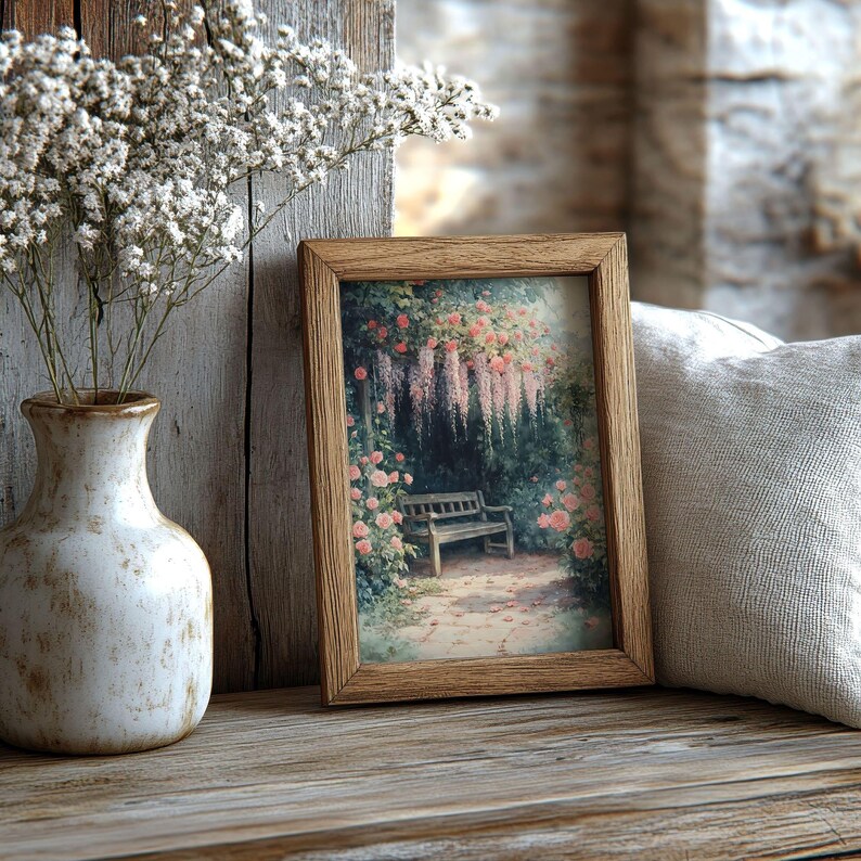 May include: A wooden picture frame with a vintage print of a garden scene. The print features a bench under a trellis with pink flowers and a cascading purple flower. The frame is sitting on a wooden surface.