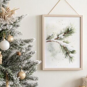 May include: A watercolor painting of a pine branch with snow on it. The background is a light green and white with a watercolor effect. The painting is framed in a light wood frame.