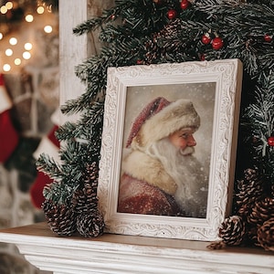 Peut inclure: Une image encadr&eacute;e en blanc de P&egrave;re No&euml;l avec un chapeau rouge et blanc et une barbe blanche. L'image est pos&eacute;e sur une chemin&eacute;e blanche avec des branches de pin et des pommes de pin.