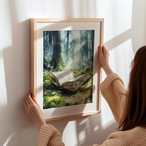 May include: A framed watercolor painting of a forest scene with a book lying open on the forest floor. The book is surrounded by green foliage and the forest is depicted in shades of green and blue.