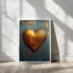 May include: A framed artwork featuring a large, textured golden heart against a teal and gold background. The heart is the focal point, set within a white frame, and placed on a wooden floor.