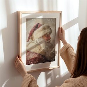 Peut inclure: Une impression encadr&eacute;e d'un portrait de P&egrave;re No&euml;l. L'image montre le visage et les &eacute;paules du P&egrave;re No&euml;l, avec un chapeau rouge et blanc et une barbe blanche. L'arri&egrave;re-plan est une sc&egrave;ne enneig&eacute;e.