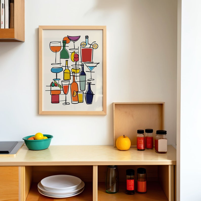 May include: A framed print of a colorful line drawing of various cocktails and drinks. The print is hanging on a white wall above a wooden shelf with jars and a bowl of lemons.
