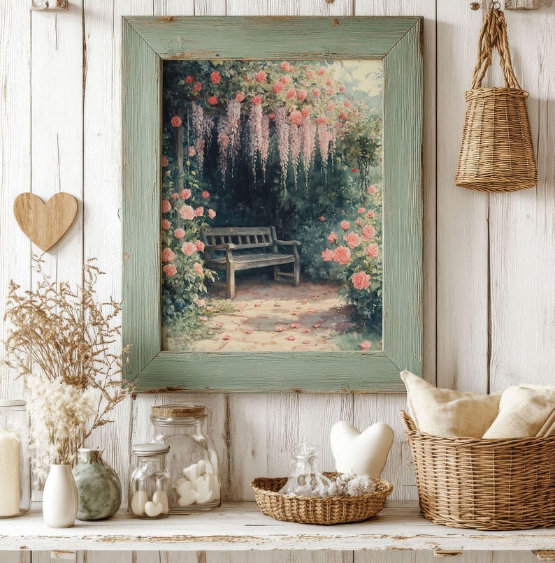May include: A framed vintage print of a garden scene with a bench under a wisteria trellis. The print is in a green frame and hangs on a white wood wall.