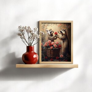 May include: A framed painting of two raccoons in a forest setting. The raccoon on the right is holding a red rose and presenting it to the raccoon on the left. Both raccoons are surrounded by pink and red roses in a basket.
