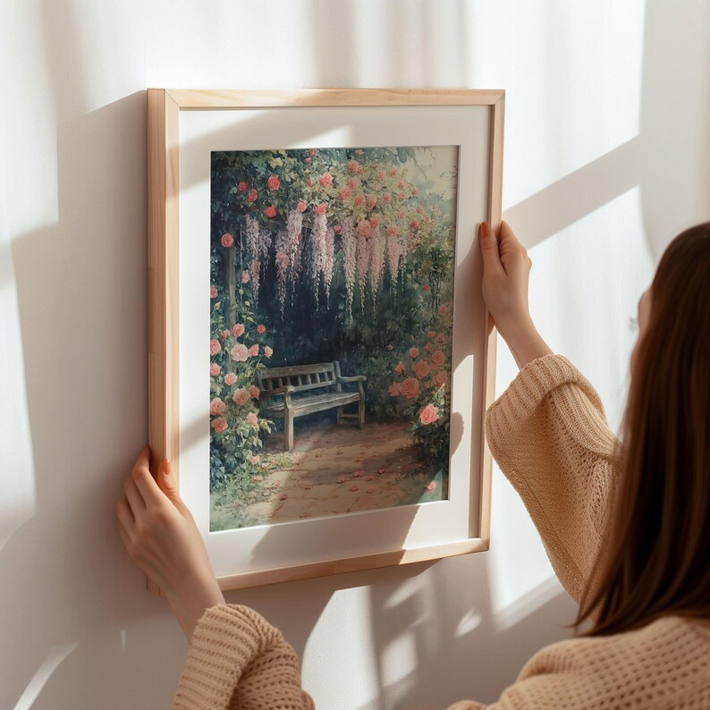 May include: A framed print of a painting depicting a wooden bench in a garden setting. The garden is filled with pink flowers and a trellis of purple wisteria. The bench is surrounded by lush greenery.