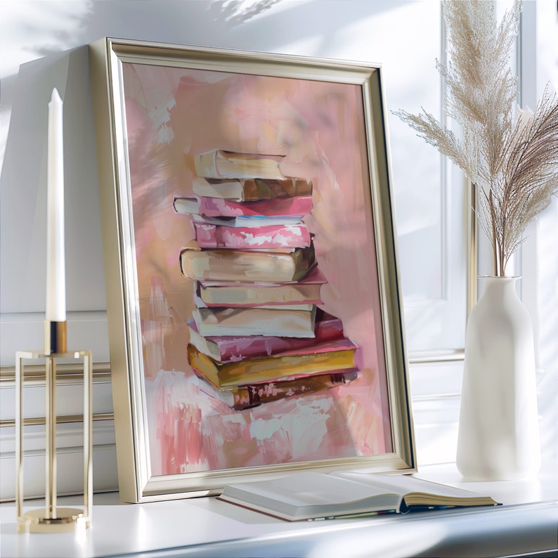 May include: A framed painting of a stack of books in various shades of pink, brown, and yellow. The books are arranged in a stack, with the top book being the smallest and the bottom book being the largest. The painting is set against a light pink background.