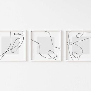Puede incluir: Tres impresiones enmarcadas blancas con dibujos de líneas negras de formas abstractas sobre un fondo blanco.