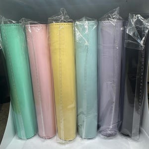 May include: A selection of pastel-coloured cylindrical items, individually wrapped in clear plastic. The colours include mint green, pink, yellow, light blue, lavender, and black. The items appear to be made of a soft material.