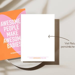 May include: A greeting card with the text "AWESOME PEOPLE MAKE AWESOME BABIES" in white on a pink heart shape, set against an orange background. A blank white card is next to it, with a website address at the bottom.