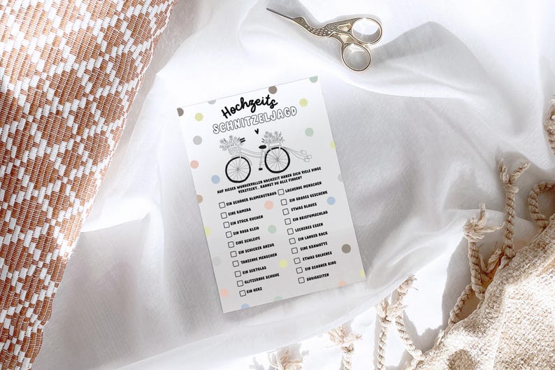 May include: A printable wedding game card with a black and white illustration of a bicycle with flowers and the text "Hochzeits Schnitzeljagd". The card has a white background with colorful polka dots.