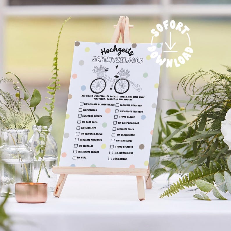 May include: A white card with a black and white illustration of a bicycle with flowers on the handlebars. The card has a checklist with the title "Hochzeits Schnitzeljagd" and a list of items to find at a wedding, such as a bouquet, a camera, a piece of cake, a blue dress, a ring, and a heart.