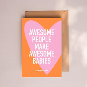 May include: A greeting card with the text "AWESOME PEOPLE MAKE AWESOME BABIES" in white on a pink heart shape, set against an orange background. The card includes a brown envelope and the word "CONGRATULATIONS" at the bottom.