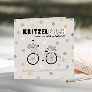 May include: A white card with a light gray background and colorful polka dots. The card says "KRITZELBUCH" in black bold letters. Below the title, it says "Hurra, es wird geheiratet!" in black letters. A black and white illustration of a bicycle with flowers in baskets on the handlebars and a white ribbon tied to the back is in the center of the card. Below the bicycle, it says "ZUM KRITZELN, KREATIV SEIN UND SPASS HABEN" in black letters.