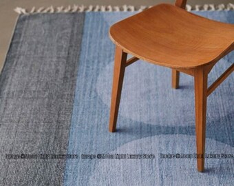 May include: A blue and gray area rug with a subtle pattern of overlapping circles. A wooden chair sits on the rug.