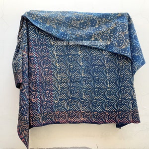 May include: A blue and white kantha quilt with a geometric pattern. The quilt is folded in half and hanging from a hook.
