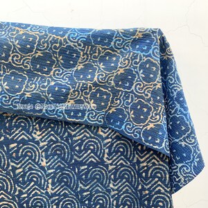 May include: A blue and white cotton fabric with a repeating pattern of stylized flowers and swirls. The fabric is folded in half, showing both sides of the pattern.