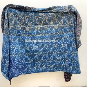 May include: A blue and white kantha quilt with a repeating pattern of stylized flowers. The quilt is made of cotton and has a hand-stitched look.
