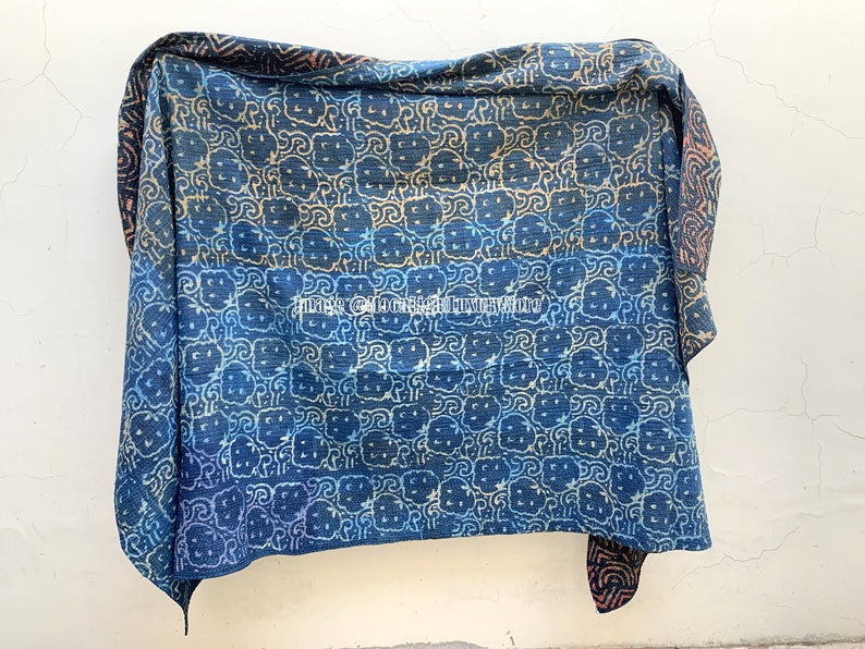 May include: A blue and white kantha quilt with a repeating pattern of stylized flowers. The quilt is made of cotton and has a hand-stitched look.