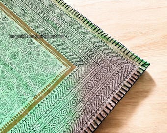 May include: A green and brown patterned fabric with a black stitched border. The fabric has a geometric design and a subtle ombre effect.