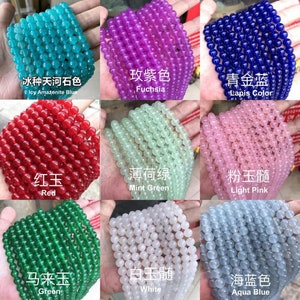 May include: Assortment of round gemstone beads in various colors, including icy blue, fuchsia, red, mint green, light pink, green, white, and aqua blue. The beads are arranged in rows on a surface.