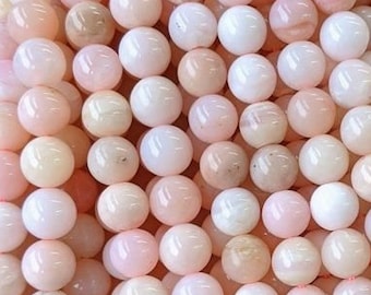 Könnte beinhalten: Eine Strähne rosa Opalperlen, jede Perle ist rund und glatt. Die Perlen sind auf einem durchsichtigen Faden aufgefädelt und bereit für die Schmuckherstellung.