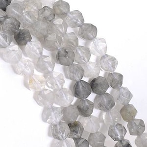 Könnte beinhalten: Eine Strähne facettierter Rauchquarzperlen in verschiedenen Grautönen. Die Perlen sind rund und haben eine leicht unregelmäßige Form. Die Perlen sind auf einem durchsichtigen Faden aufgefädelt.