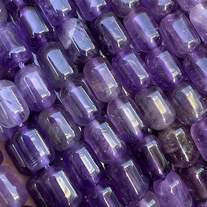 Puede incluir: Una hebra de cuentas de piedra preciosa de amatista púrpura, cada cuenta tiene una forma rectangular de barril con un acabado liso y pulido.