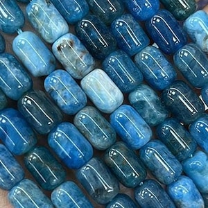 Puede incluir: Una hebra de cuentas de piedras preciosas azules y verdes. Las cuentas son de forma ovalada y tienen un acabado liso y pulido.