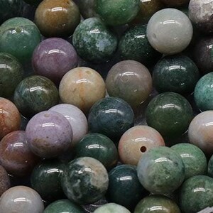 Peut inclure: Gros plan sur un récipient rempli de perles rondes en agate de couleur verte, brune et violette. Les perles sont lisses et polies, avec une variété de motifs et de couleurs.