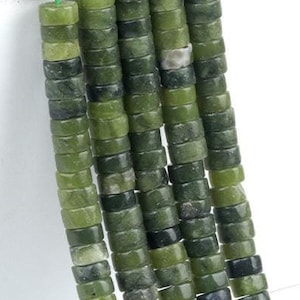 Könnte beinhalten: Eine Strähne grüner Jadeperlen, jede Perle ist ein Zylinder mit leicht quadratischer Form. Die Perlen sind auf einem grünen Faden aufgereiht.