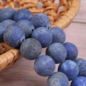 May include: A strand of dark blue lapis lazuli beads with a rough, matte finish. The beads are round and have a natural, earthy look.
