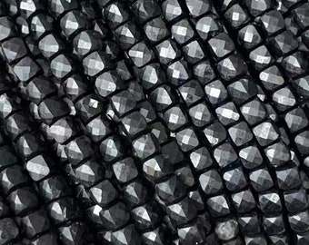 Könnte beinhalten: Eine Schnur schwarzer Turmalin-Perlen, facettiert und poliert, mit quadratischer Form. Die Perlen sind auf einem durchsichtigen Faden aufgereiht. Das Bild enthält den Text "Black Tourmaline".