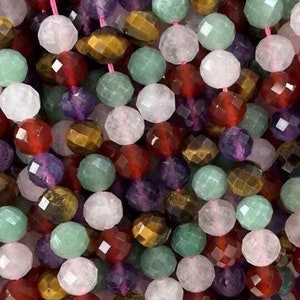 Può includere: Un filo di perline di pietre preziose sfaccettate in vari colori, tra cui verde, rosso, marrone, viola e bianco. Le perline sono infilate su un filo elastico trasparente.