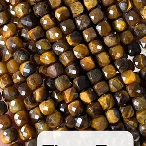 Puede incluir: Hilos de cuentas facetadas de piedra preciosa ojo de tigre. Las cuentas son una mezcla de tonos marrón dorado y marrón oscuro, con forma cuadrada y un acabado pulido y brillante. Se incluye el texto "Tiger Eye".