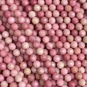 May include: A strand of pink and white gemstone beads. The beads are faceted and have a smooth, polished finish.