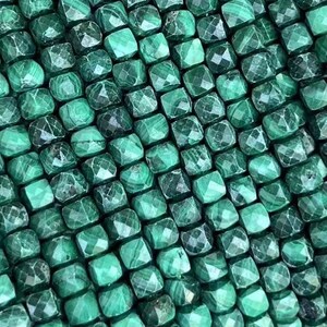 Pode incluir: Um fio de contas de malaquita verde, cada conta é facetada e tem formato quadrado.