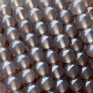 May include: A strand of grey agate beads. The beads are round and smooth, with a slightly translucent appearance.