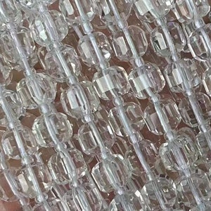 Puede incluir: Una hebra de cuentas de cristal facetadas transparentes. Las cuentas están enhebradas en un hilo blanco y tienen un diámetro de aproximadamente 8 mm.