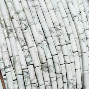 May include: A strand of white and grey cylindrical beads made of natural turquoise. The beads are approximately 1.2 cm long and have a smooth, polished finish.