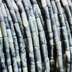 May include: A strand of gray and white marbled stone beads. The beads are cylindrical and have a smooth, polished finish.