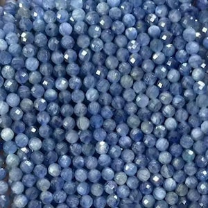 Peut inclure: Un brin de perles de pierres précieuses bleues, facettées et rondes, enfilées pour la fabrication de bijoux. Les perles sont de couleur bleu clair et ont un léger éclat iridescent.