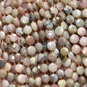 May include: A strand of pink opal beads with a faceted finish. The beads are a mix of light and dark pink with white and gray inclusions. The beads are strung on a clear elastic cord.