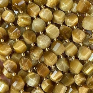 May include: A strand of golden tiger's eye beads, each bead is faceted and has a unique pattern of brown and gold. The beads are strung on a clear thread and are ready to be used for jewellery making.